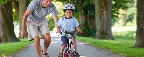 Kind mit Fahrradhelm übt Fahrradfahren mit dem Papa