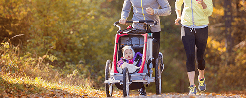 Joggende Eltern mit Kind im Sportkinderwagen